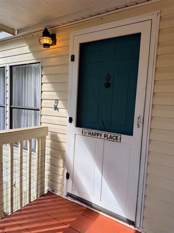 A teal and white screen door with a sign sits on a wooden porch — 14790 NW 72ND COURT, CHIEFLAND, FL