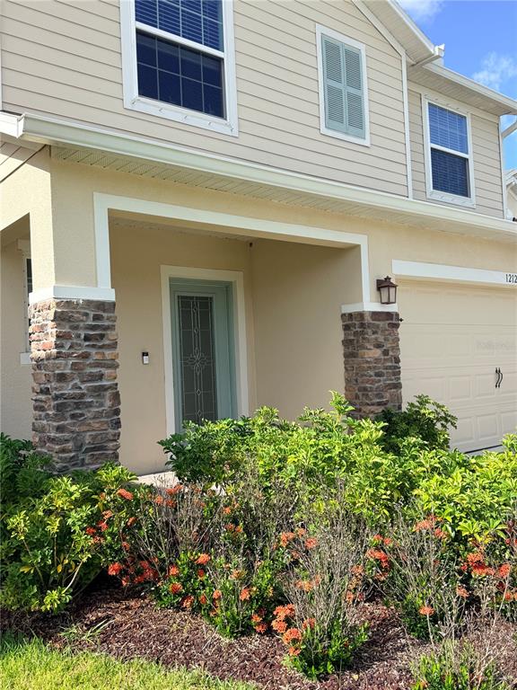 A two-story house exterior features tan siding, stone-accented columns, and a light green front door — 1212 CANFIELD CIRCLE SE, PALM BAY, FL