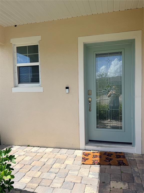 A light-colored exterior wall features a green front door with a glass insert and window — 1212 CANFIELD CIRCLE SE, PALM BAY, FL