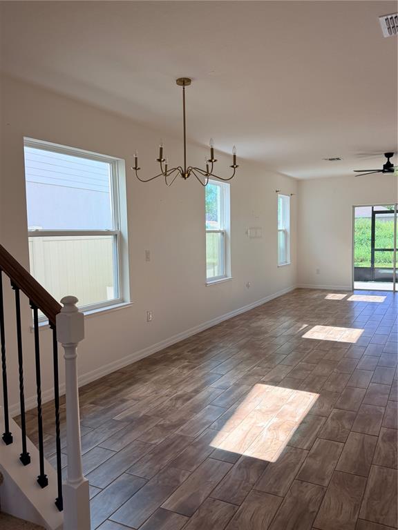 An open-concept room features wood-look tile flooring, a brass chandelier, and a staircase — 1212 CANFIELD CIRCLE SE, PALM BAY, FL