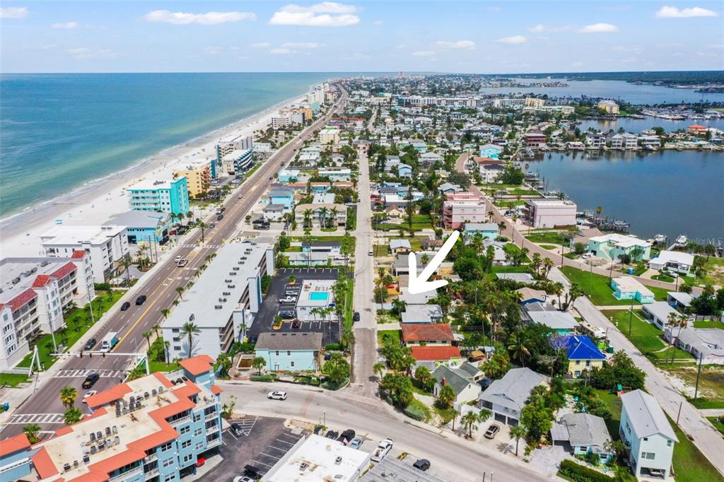 An aerial view shows a coastal neighborhood with a white arrow pointing to a house — 14023 PALM STREET, MADEIRA BEACH, FL