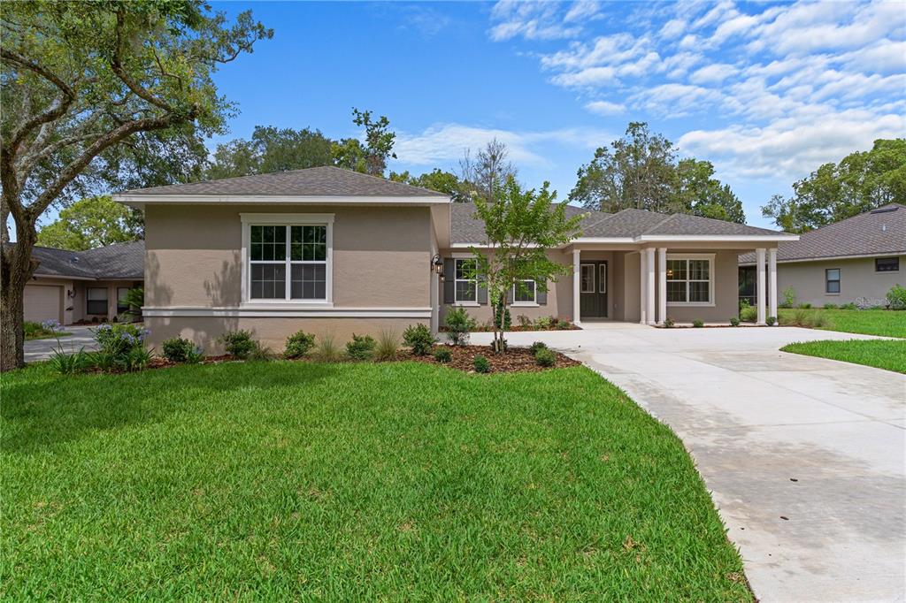 A single-story house with a beige stucco exterior, a concrete driveway, and a grassy lawn — 3030 W BERMUDA DUNES DRIVE, LECANTO, FL