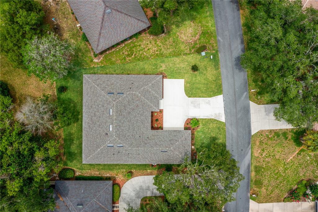 An aerial view shows a house with a gray roof, a concrete driveway, and surrounding trees — 3030 W BERMUDA DUNES DRIVE, LECANTO, FL