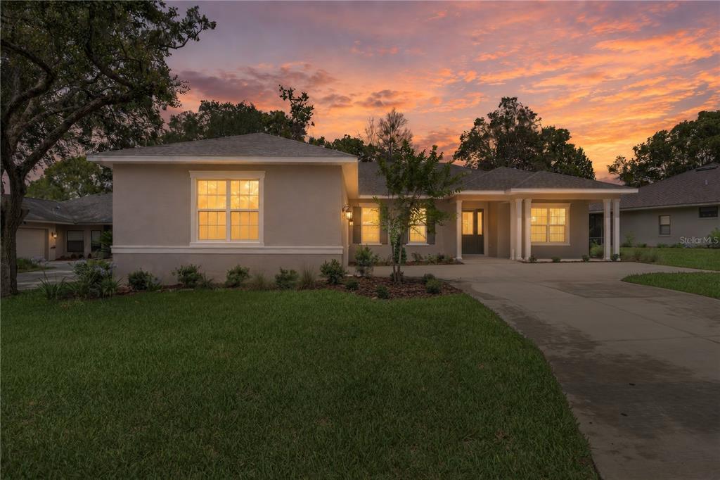 A single-story house with a concrete driveway and lawn at sunset — 3030 W BERMUDA DUNES DRIVE, LECANTO, FL