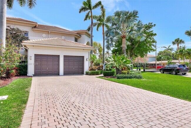 A two-car garage with brown doors sits at the end of a paved driveway — 2844 NE 26th Avenue, Lighthouse Point FL 33064, LIGHTHOUSE POINT, FL