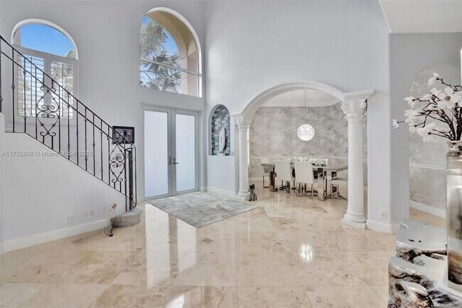 A bright foyer features marble floors, a wrought iron staircase, and an arched dining area — 2844 NE 26th Avenue, Lighthouse Point FL 33064, LIGHTHOUSE POINT, FL