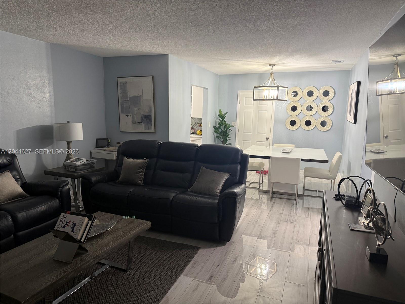 A living and dining area features light blue walls, tile flooring, and dark leather furniture — MARGATE, FL