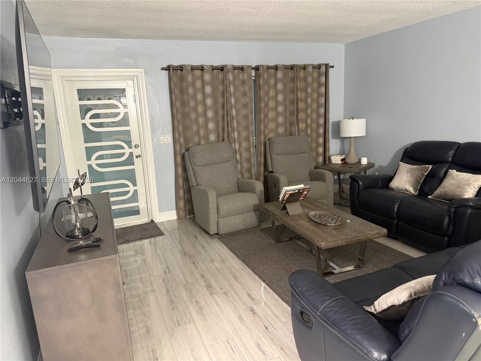 A living room features light wood-look tile floors, two recliners, and dark leather sofas — MARGATE, FL