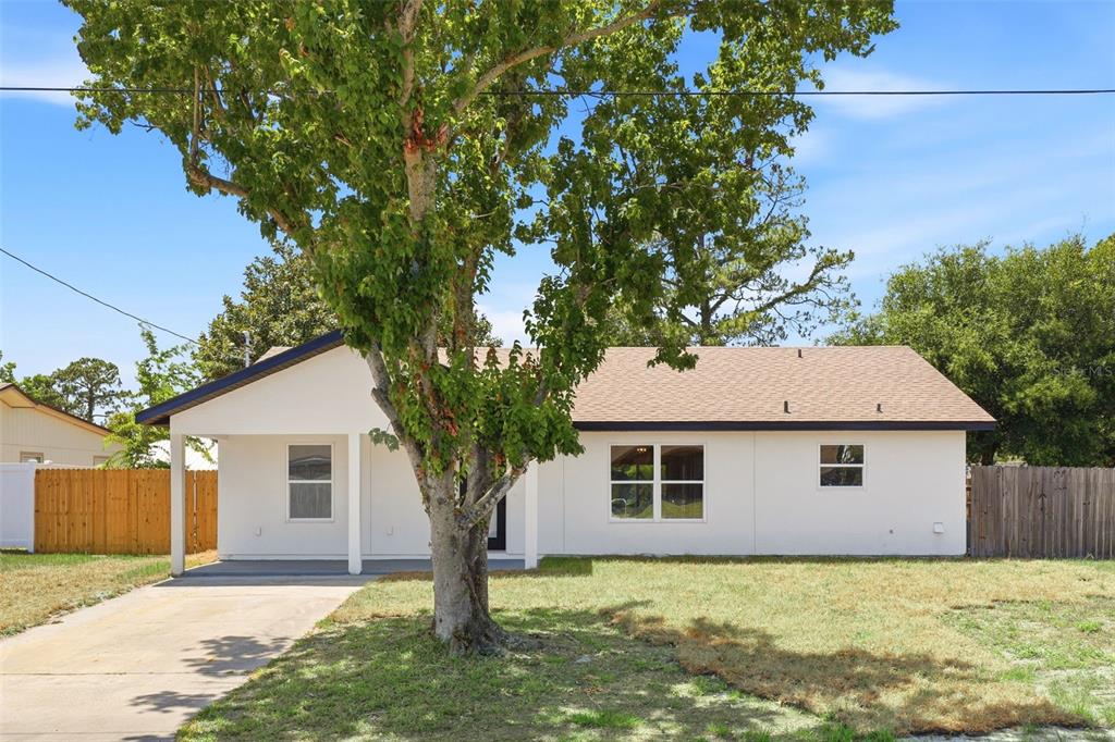 A single-story white house with a covered front porch and a large tree in front — 5424 FLINT ROAD, COCOA, FL