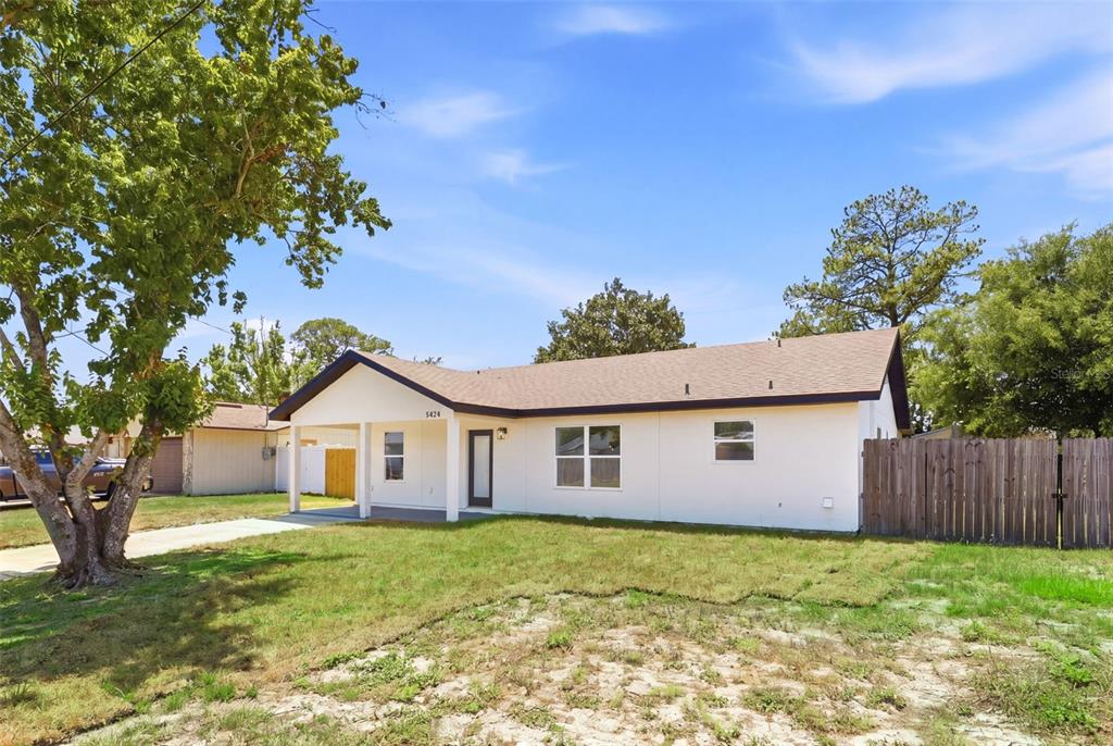 A white, single-story house with a covered front porch and a wooden fence — 5424 FLINT ROAD, COCOA, FL