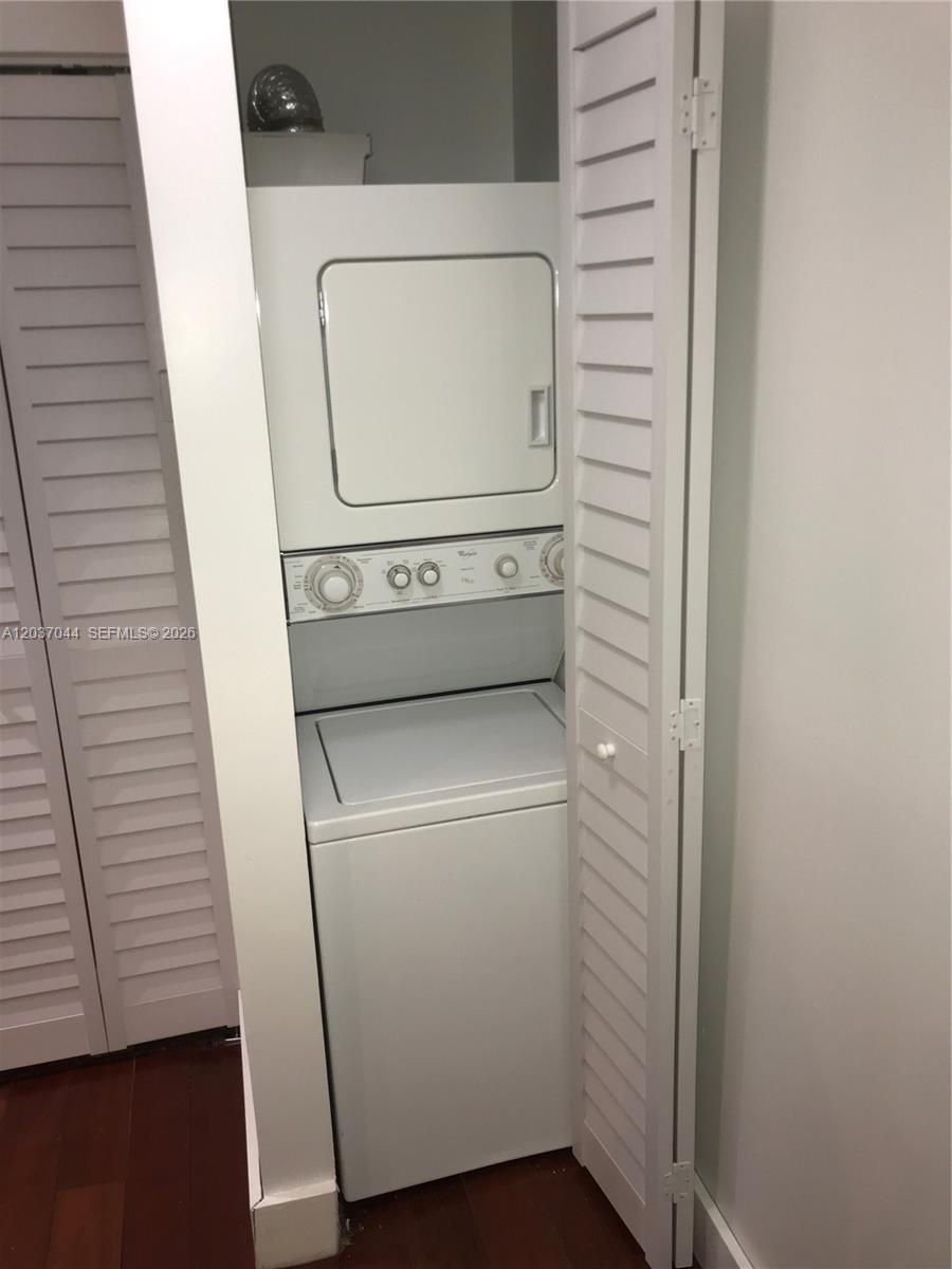 A white stacked washer and dryer unit is housed inside a closet with louvered doors — 731 6th St, Miami Beach FL 33139, MIAMI BEACH, FL