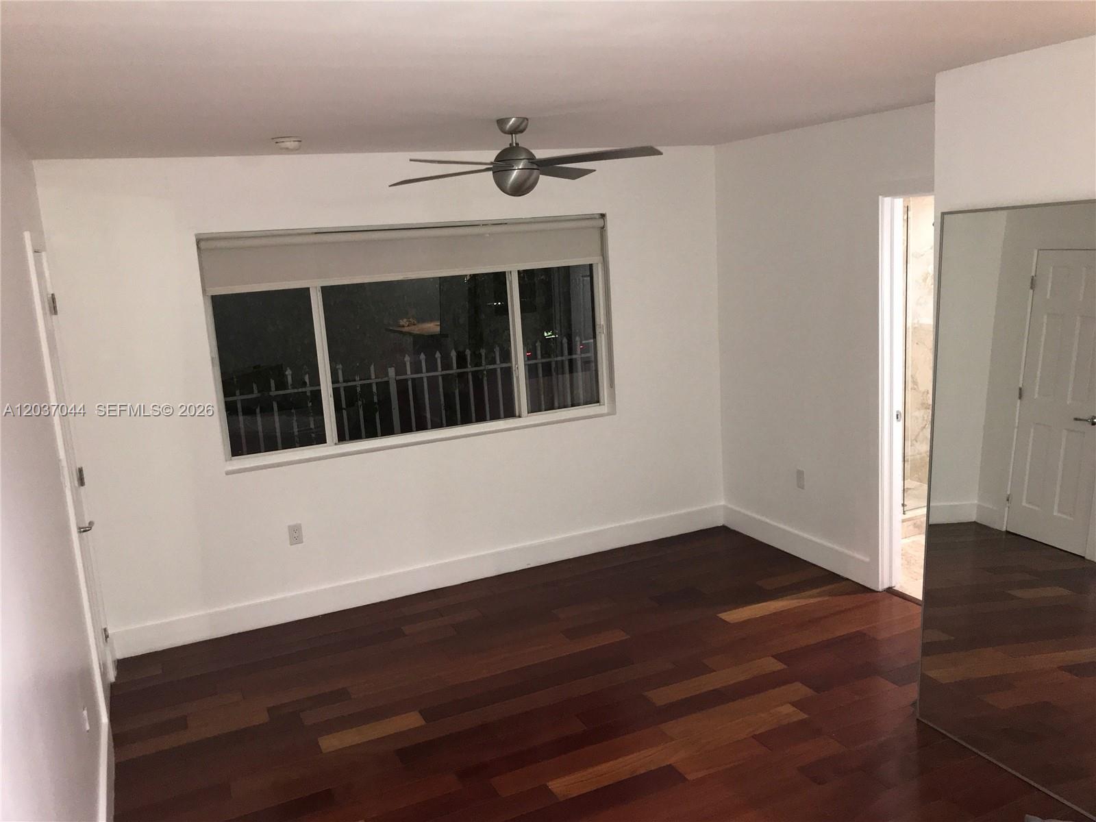 An empty bedroom features dark hardwood floors, white walls, a ceiling fan, and a large window — 731 6th St, Miami Beach FL 33139, MIAMI BEACH, FL
