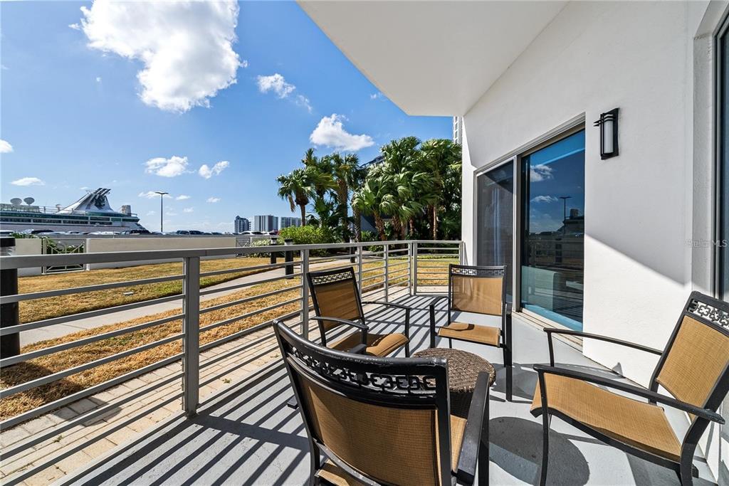 A balcony with patio furniture overlooks a parking lot and a cruise ship — 1209 E CUMBERLAND AVENUE UNIT 508, TAMPA, FL
