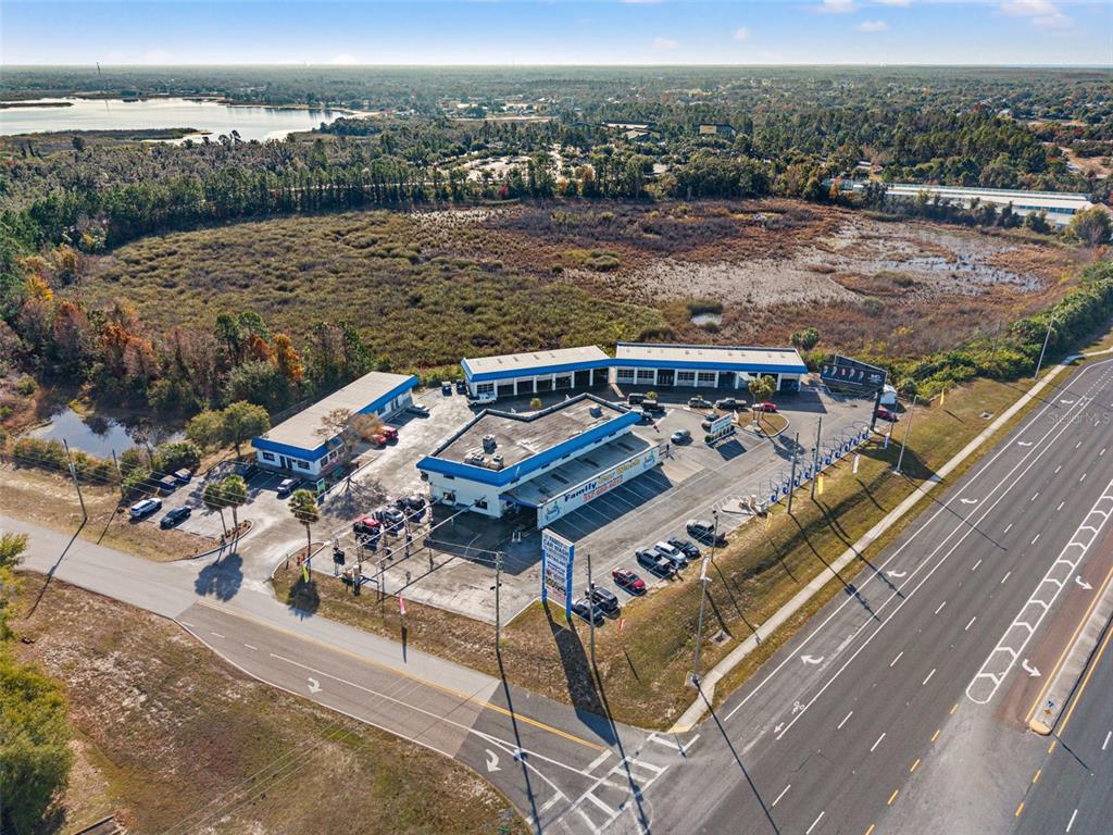 An aerial view shows a car wash facility with multiple buildings, parking areas, and surrounding land — 1108 COMMERCIAL WAY, SPRING HILL, FL