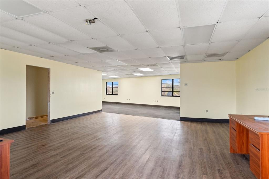 An office space features light yellow walls, wood-look flooring, and a drop ceiling — 1108 COMMERCIAL WAY, SPRING HILL, FL