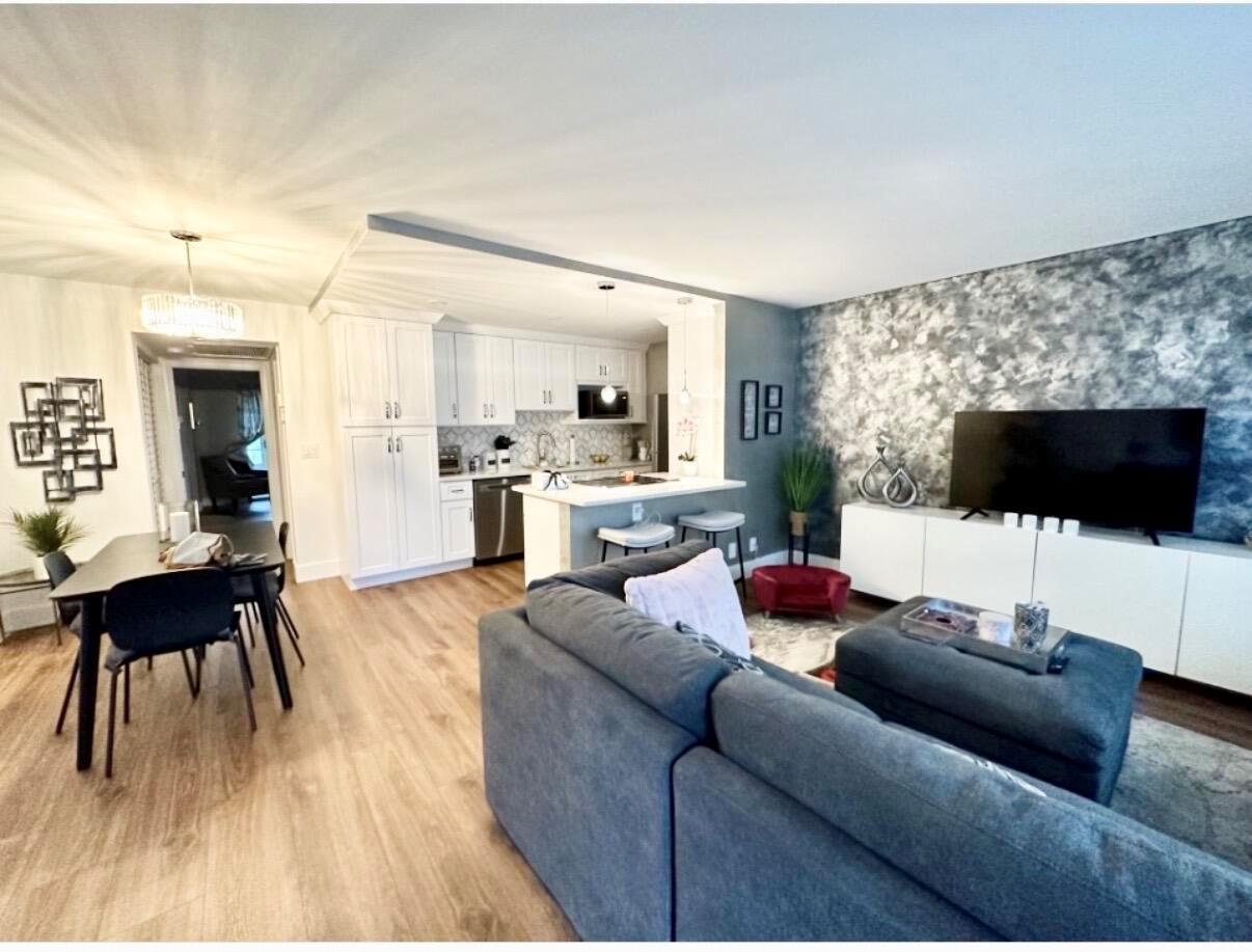 An open-concept living room and kitchen with white cabinets, wood flooring, and a textured wall — 1044 Cambridge C, Deerfield Beach FL 33442, DEERFIELD BEACH, FL