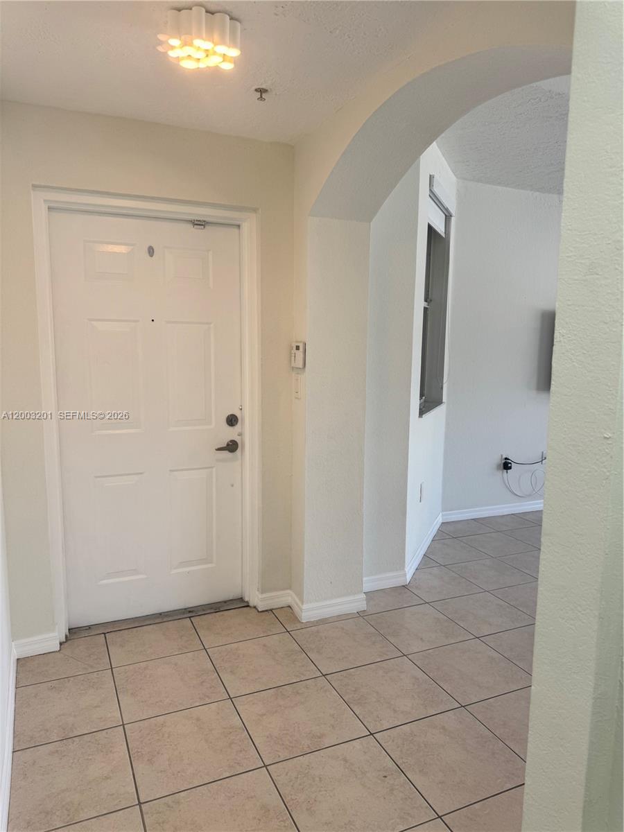 An entryway features a white door, tiled flooring, and an arched transition to another room — 8826 W Flagler St # 102, Miami FL 33174, MIAMI, FL