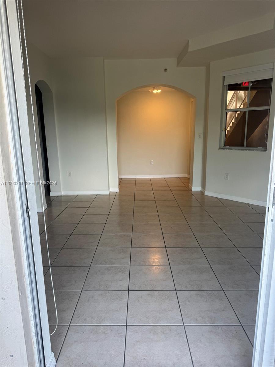 An interior view shows a tiled room with an arched entryway leading to a lit alcove — 8826 W Flagler St # 102, Miami FL 33174, MIAMI, FL
