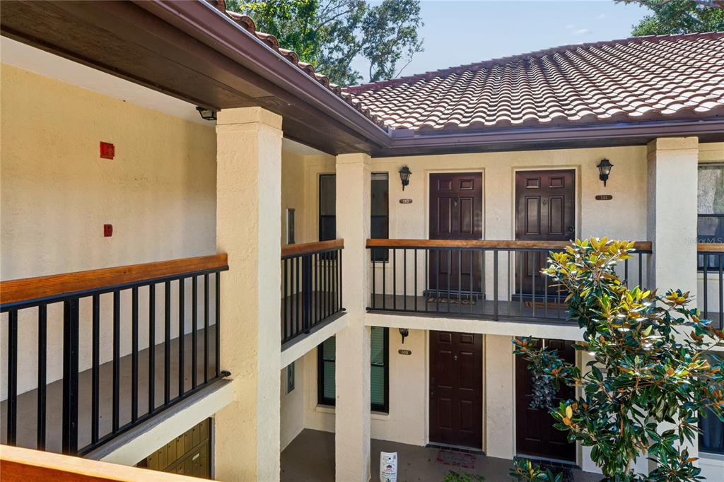 An exterior view of a two-story apartment building with balconies and dark brown doors — 110 HAMMOCK PINE BOULEVARD, CLEARWATER, FL