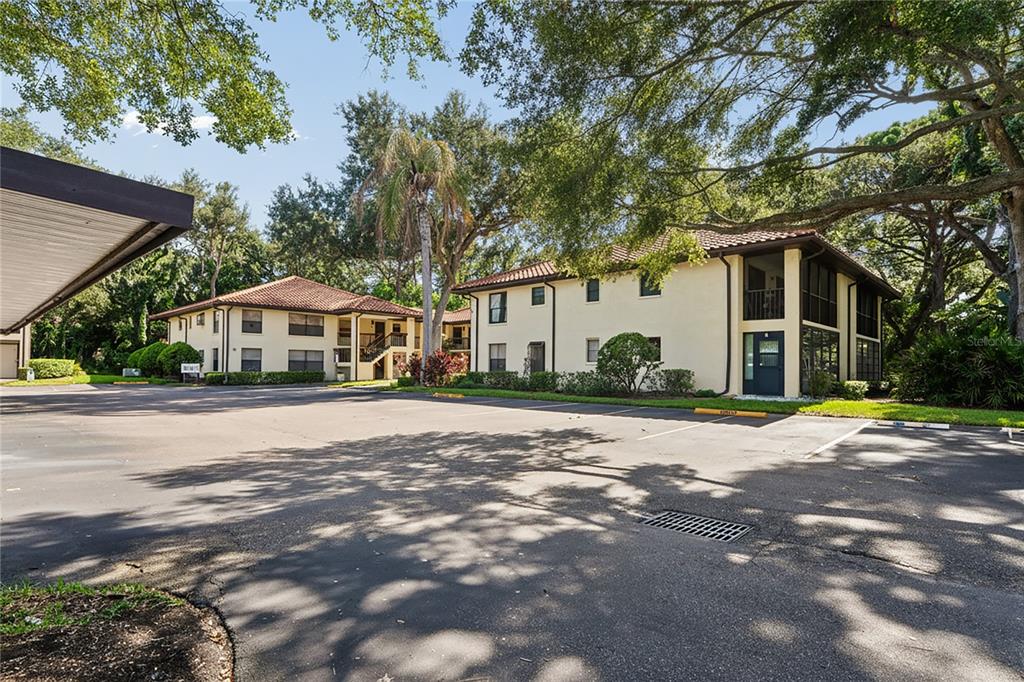A two-story apartment building with a parking lot and mature trees in the foreground — 110 HAMMOCK PINE BOULEVARD, CLEARWATER, FL