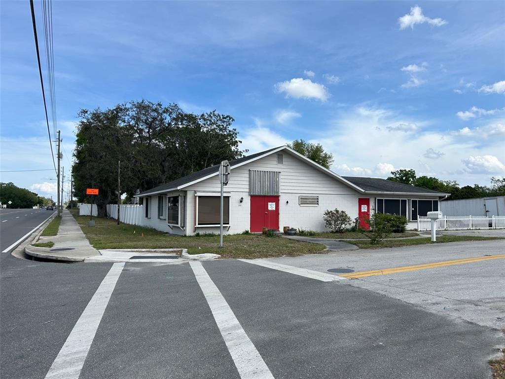 A single-story white building with red doors sits on a corner lot near a road — 2405 SOUTH STREET, LEESBURG, FL