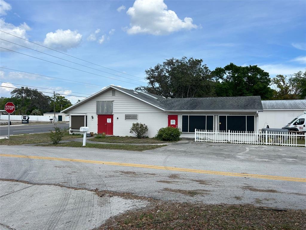 A single-story commercial building with white siding, red doors, and a white picket fence — 2405 SOUTH STREET, LEESBURG, FL