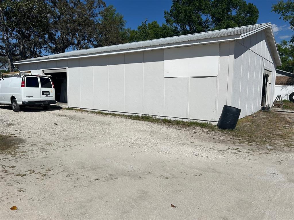 A white metal-sided workshop building sits on a gravel lot with a van parked inside — 2405 SOUTH STREET, LEESBURG, FL
