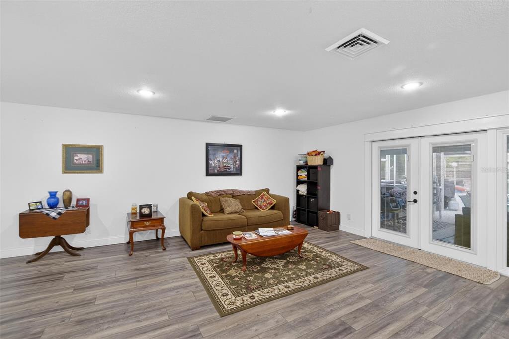 A living room features wood-look flooring, a brown sofa, and glass doors leading outside — 723 W PINEDALE DRIVE, PLANT CITY, FL