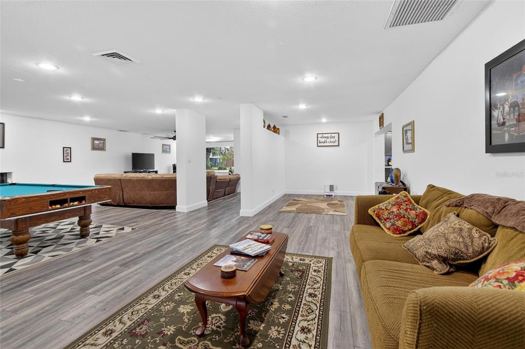 A spacious living area features wood-look flooring, a pool table, and a brown sofa — 723 W PINEDALE DRIVE, PLANT CITY, FL