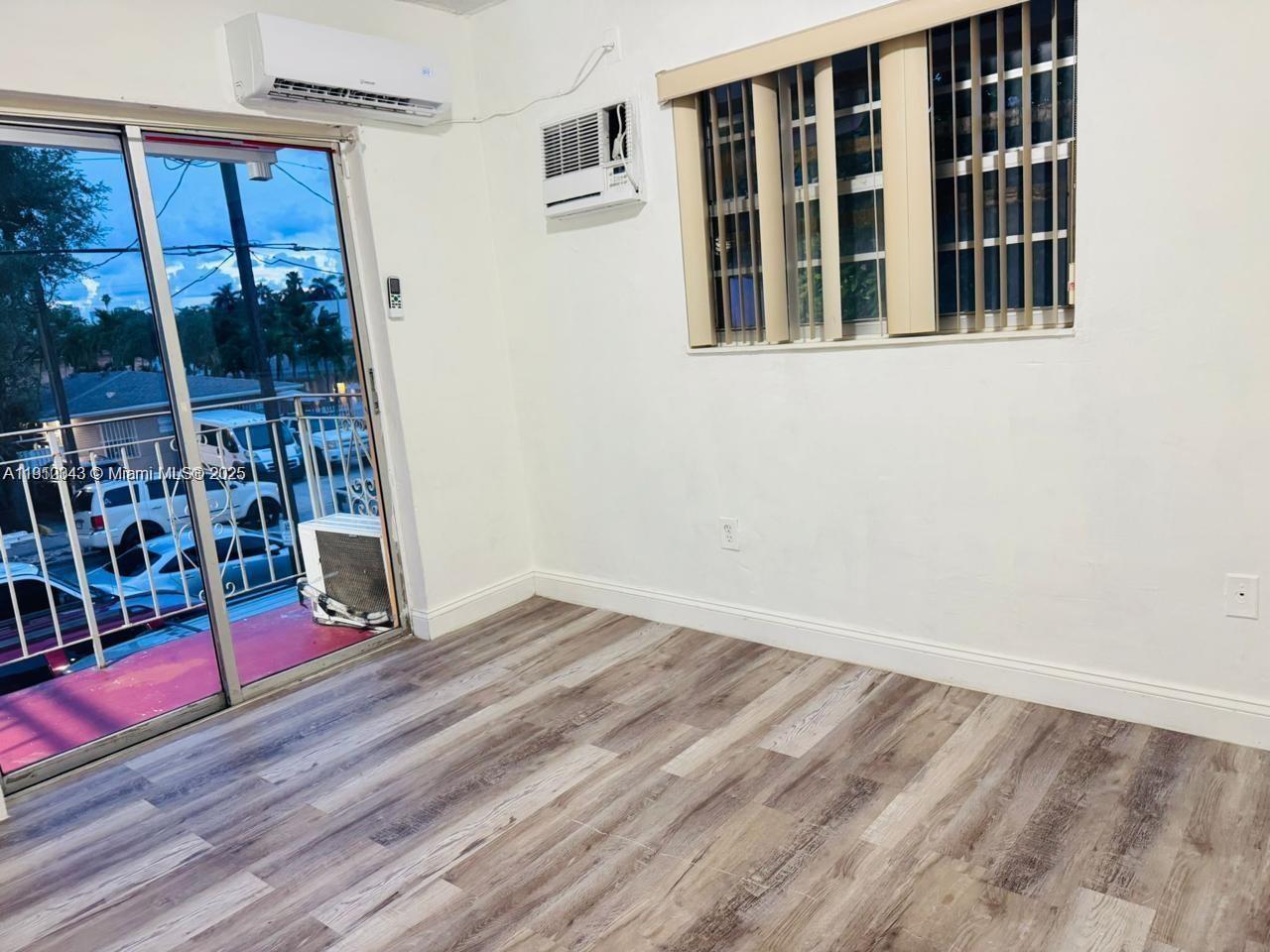 An interior room features wood-look flooring, a sliding glass door, a window, and two air conditioners — 932 NW 5th St, Miami FL 33128, MIAMI, FL