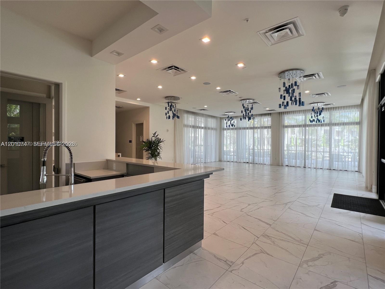 A modern room features a dark gray bar, marble-look tile floors, and blue pendant lighting — 8167 NW 41st St # 308, Doral FL 33166, DORAL, FL