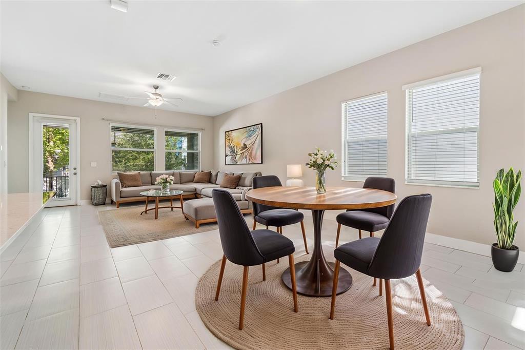 An open-concept living and dining area features tile flooring, a sectional sofa, and a table — 7409 S KISSIMMEE STREET, TAMPA, FL