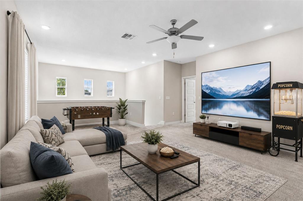 A furnished media room features a large projection screen, a foosball table, and a sectional sofa — 7409 S KISSIMMEE STREET, TAMPA, FL