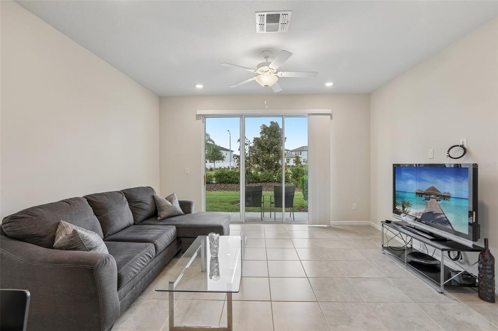 A living room features a grey sectional sofa, glass coffee table, television, and sliding glass doors — 31337 AMBERVIEW BEND, WESLEY CHAPEL, FL