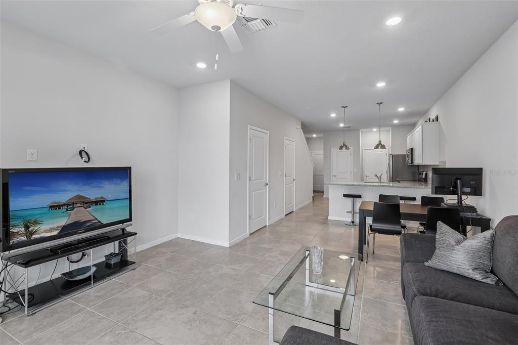 An open-concept living room and kitchen featuring tile flooring, a ceiling fan, and neutral walls — 31337 AMBERVIEW BEND, WESLEY CHAPEL, FL