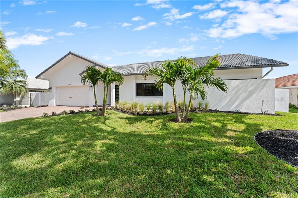 A white single-story house with a two-car garage, palm trees, and a manicured lawn — 4973 60TH AVENUE S, ST PETERSBURG, FL