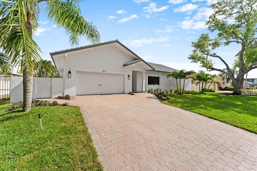 A single-story house with a white exterior, a paved driveway, and a two-car garage — 4973 60TH AVENUE S, ST PETERSBURG, FL