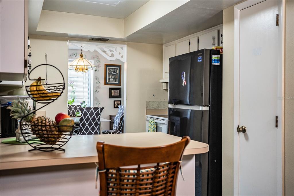 A kitchen with a black refrigerator, a breakfast bar, and a view into a dining area — 85 COUNTRY CLUB LANE, MULBERRY, FL