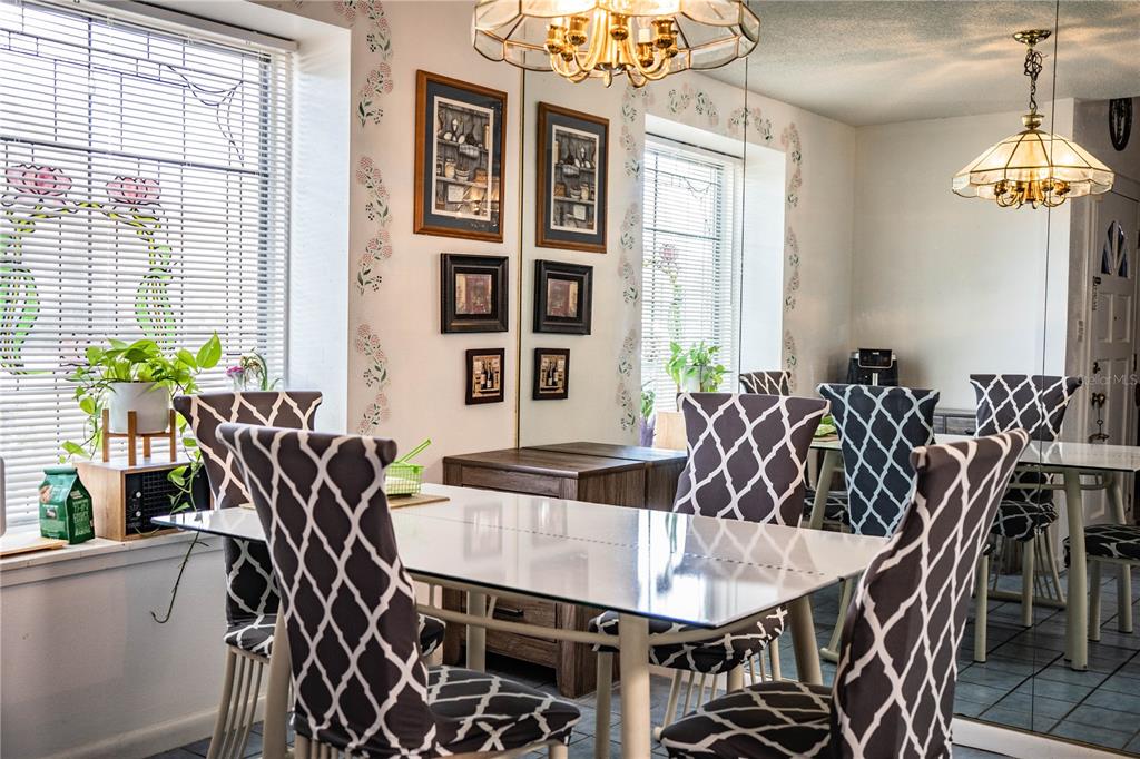 A dining room features a glass-top table, patterned chairs, a mirrored wall, and two chandeliers — 85 COUNTRY CLUB LANE, MULBERRY, FL