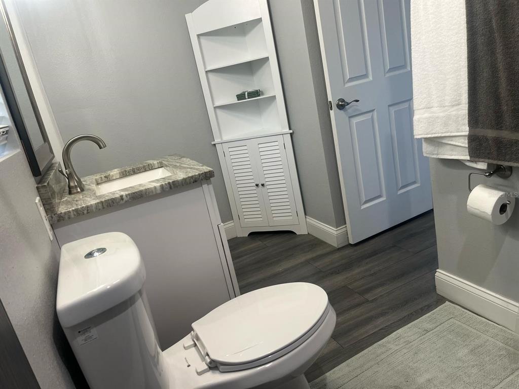 A bedroom features a wooden bed frame, gray walls, and dark wood-look plank flooring — 4803 ROUSH AVENUE UNIT STUDIO, ORLANDO, FL