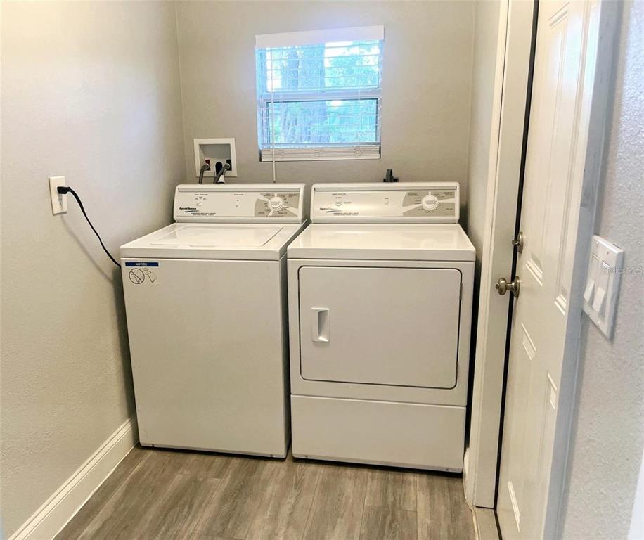 A bathroom features a granite-topped vanity, wood-look flooring, and a tiled shower with a curtain — 4803 ROUSH AVENUE UNIT STUDIO, ORLANDO, FL