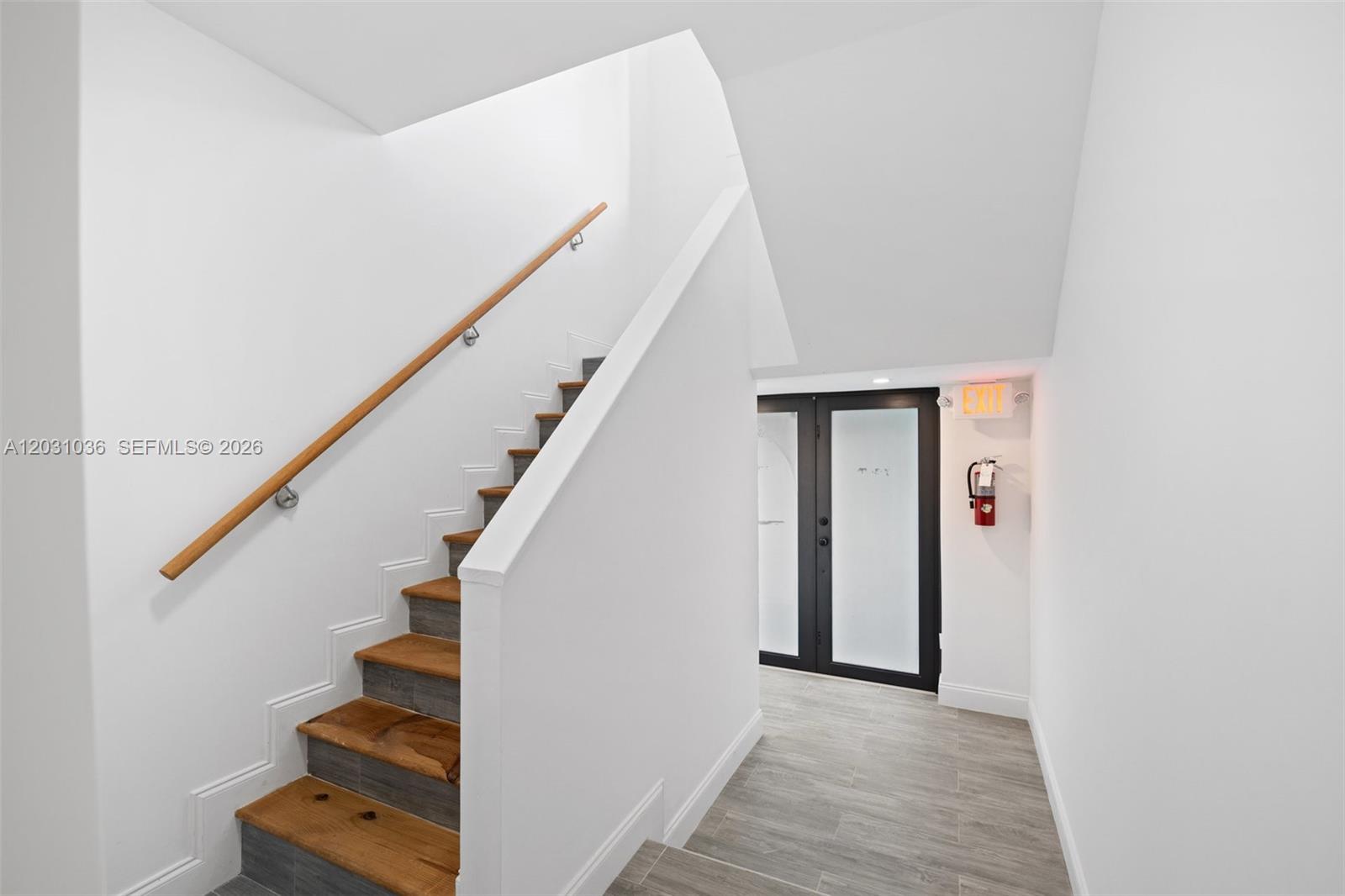 A staircase with wooden treads and a handrail leads to a landing with a door — 1721 SW 13th St # 4, Miami FL 33145, MIAMI, FL