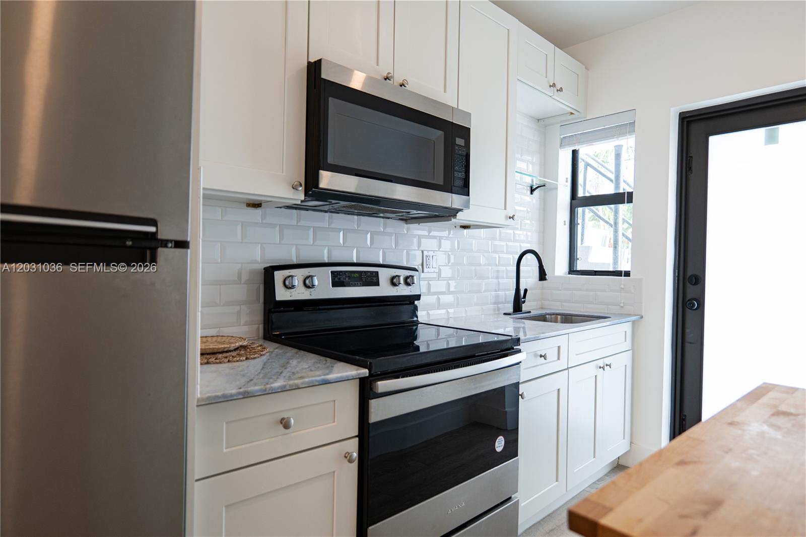 A kitchen features white cabinets, stainless steel appliances, a subway tile backsplash, and marble countertops — 1721 SW 13th St # 4, Miami FL 33145, MIAMI, FL