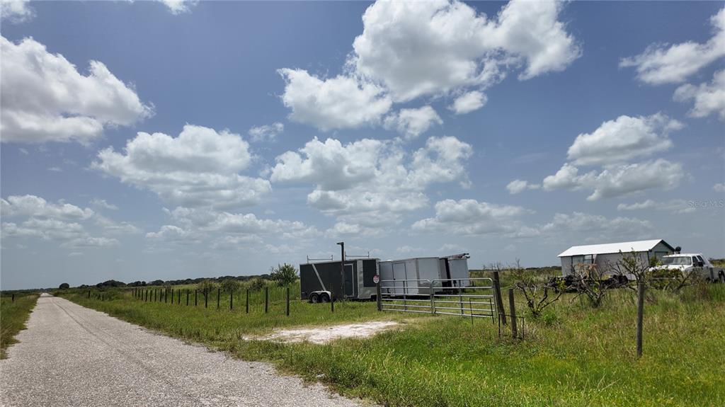 A gravel road runs alongside a fenced field containing several trailers and a small building — 2001/2011 GRAHAM ROAD, PUNTA GORDA, FL