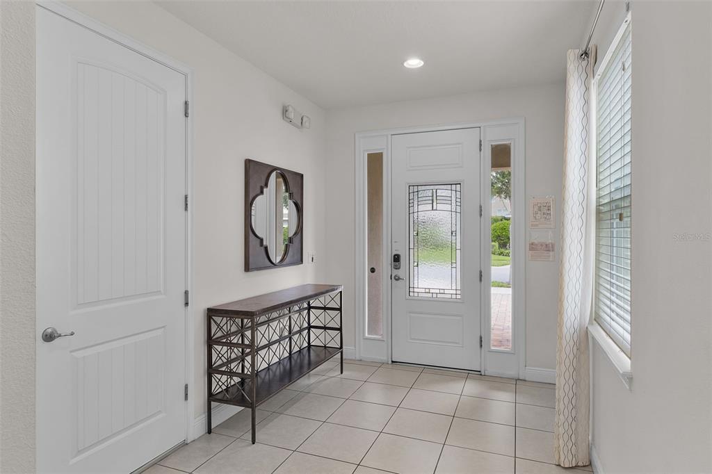 An entryway features tile flooring, a white front door with glass, and a metal console table — 7513 MARKER AVENUE, KISSIMMEE, FL