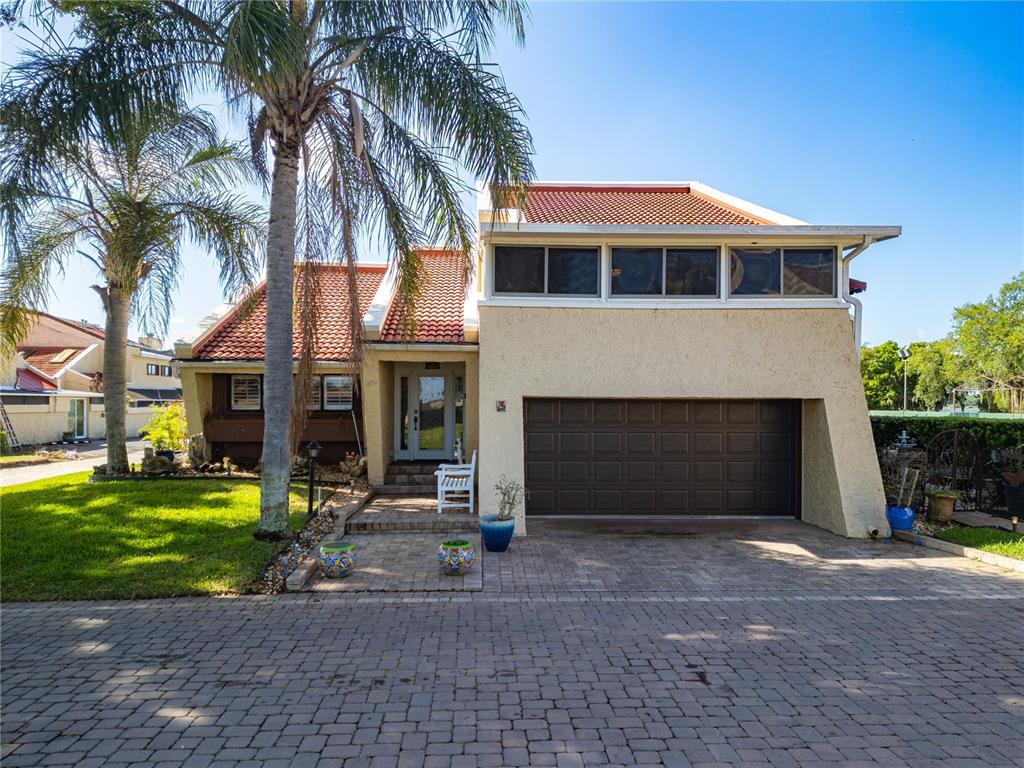 A two-story house with a brown garage door, red tile roof, and a palm tree — 4 CASARENA COURT, WINTER HAVEN, FL