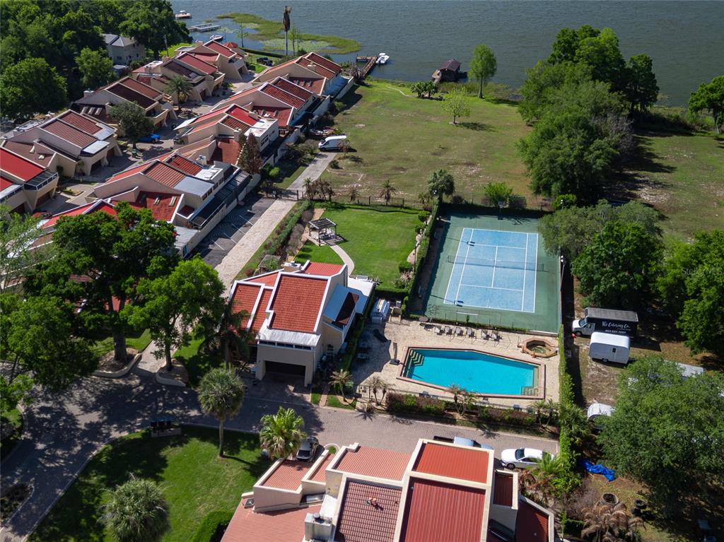 An aerial view shows a residential complex with a tennis court, pool, and waterfront access — 4 CASARENA COURT, WINTER HAVEN, FL