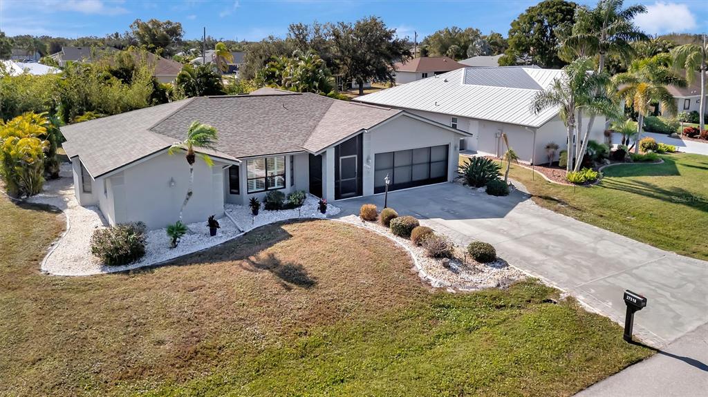 An aerial view shows a single-story house with a gray roof, garage, and landscaped yard — 27518 TIERRA DEL FUEGO CIRCLE, PUNTA GORDA, FL