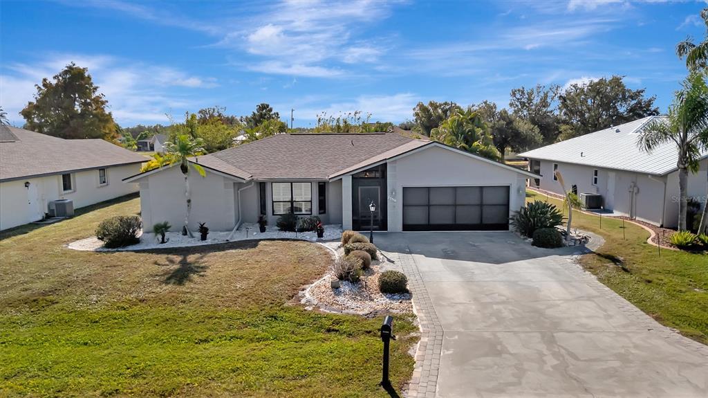 A single-story house with a gray exterior, a paved driveway, and a two-car garage — 27518 TIERRA DEL FUEGO CIRCLE, PUNTA GORDA, FL