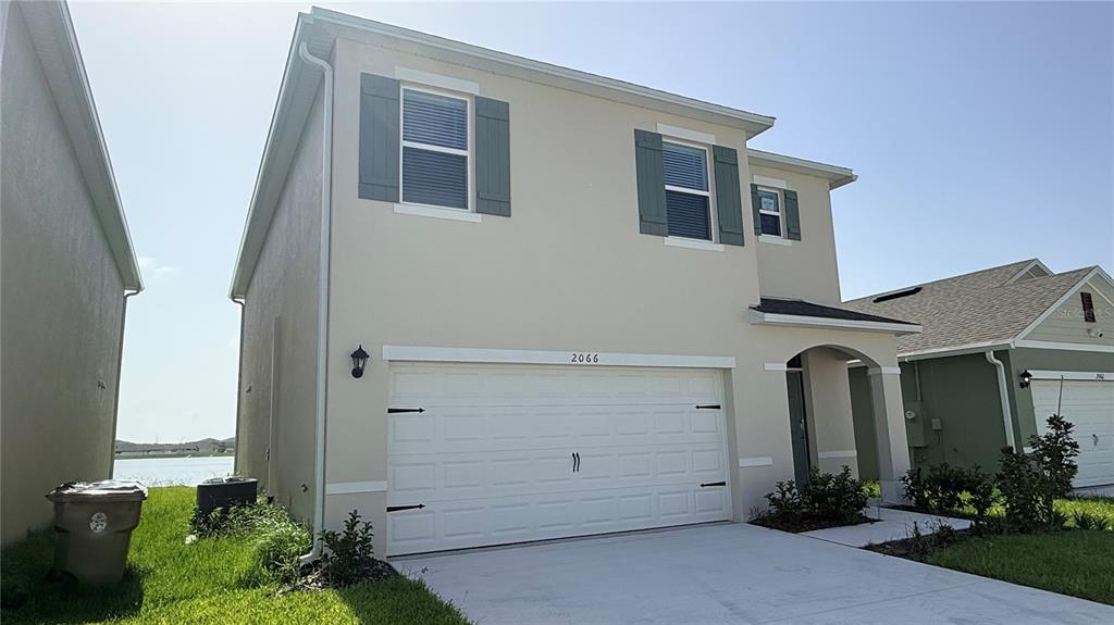 A two-story house with a white garage, beige stucco siding, and dark green shutters — 2066 WALNUT CREEK DRIVE, KISSIMMEE, FL